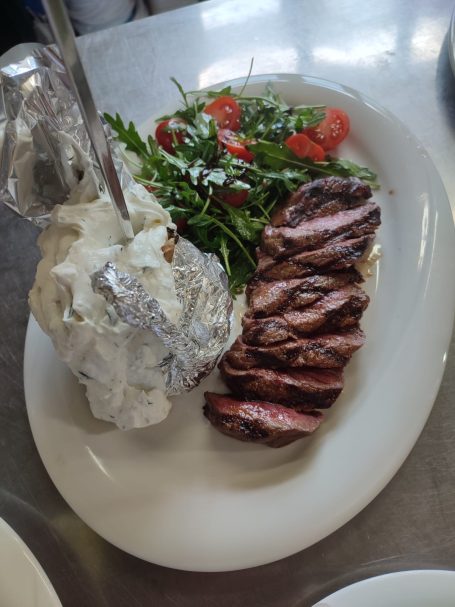 Gegrilltes Steak mit Salat und einer Backkartoffel mit Sauerrahm.