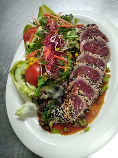 Salatplatte mit Thunfischsteak, Sesam, buntem Gemüse und einer scharfen Sauce.